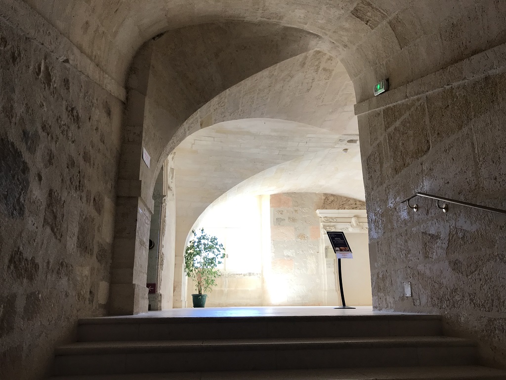 Ein Treppenaufgang im Schlaftrakt der Abbaye aux Dames. Auf dem Treppenabsatz scheint hell die Sonne. Die Decke des Treppenabsatzes hat die Form eines Gewölbes