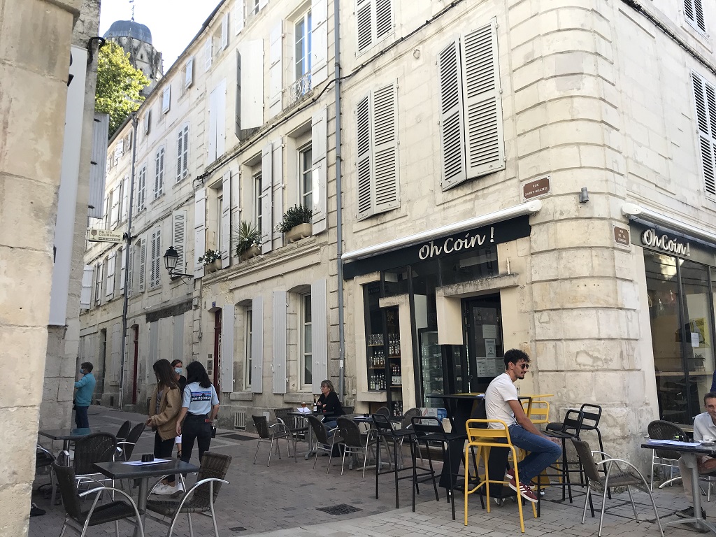 Auf einer Straßenecke stehen vor einem Café Tische. Cafés und Bistros sind vor allem bei jungen Leuten beliebt